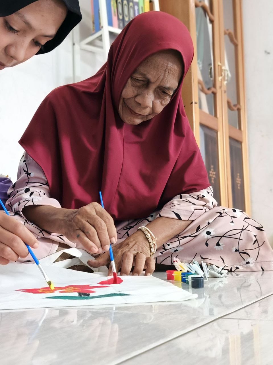 Lansia aktif membuat kerajinan lukis di atas canvas tas