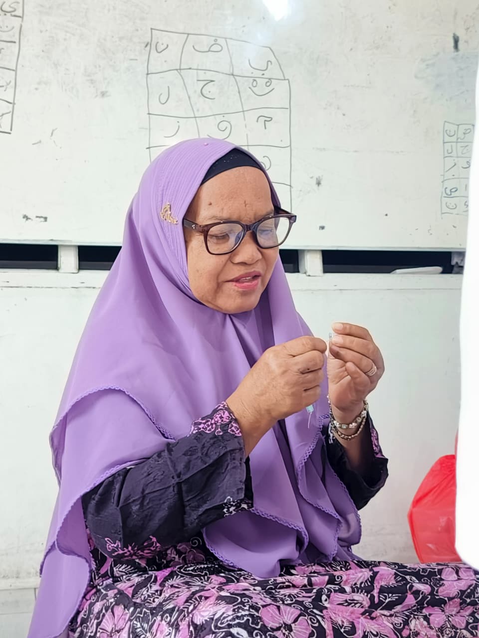 Lansia Almarhamah Fokus Menyusun Manik Manik