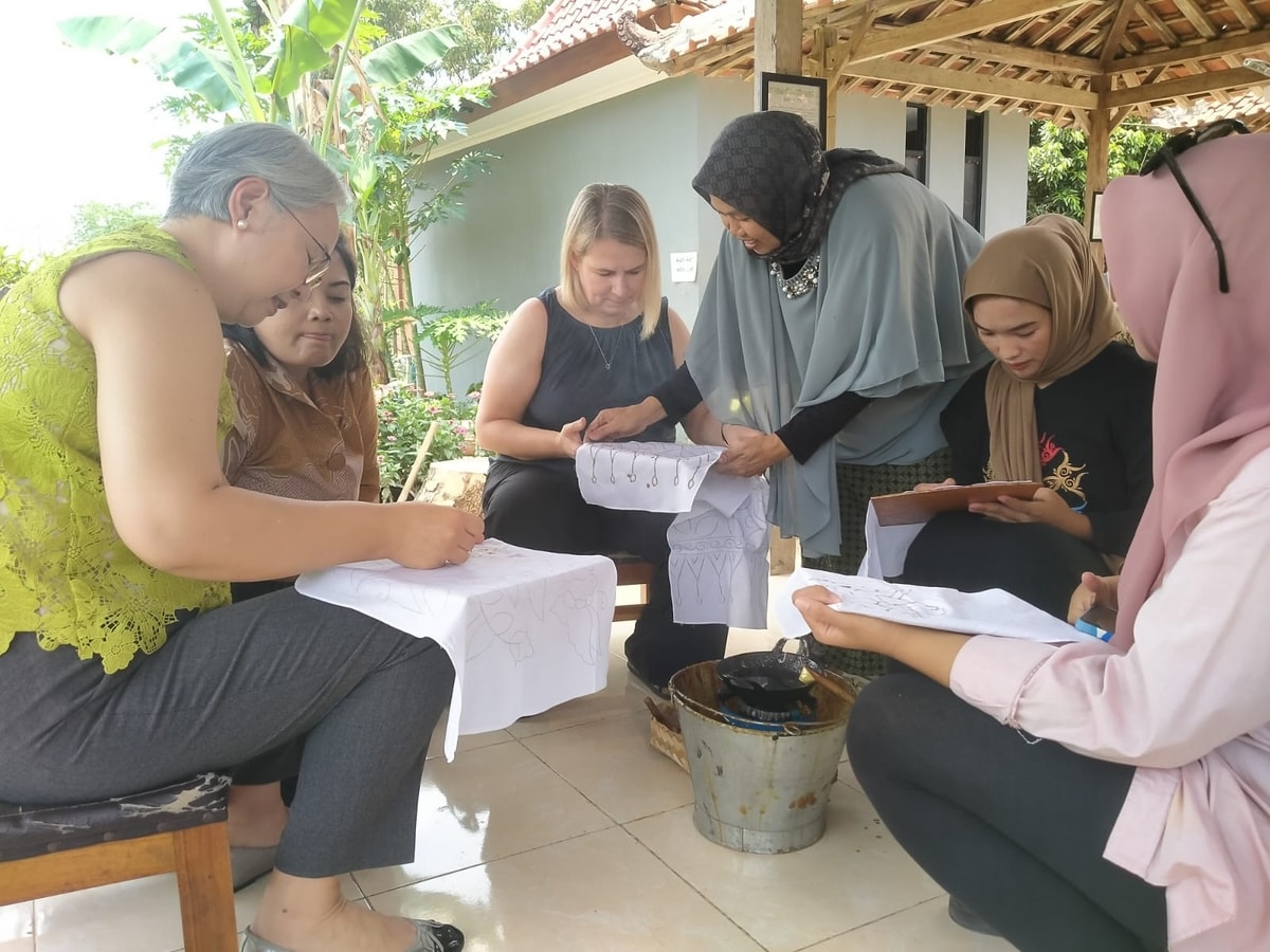 Para wisatawan internasional berinteraksi langsung dengan para perajin batik untuk membuat karya batik tulis