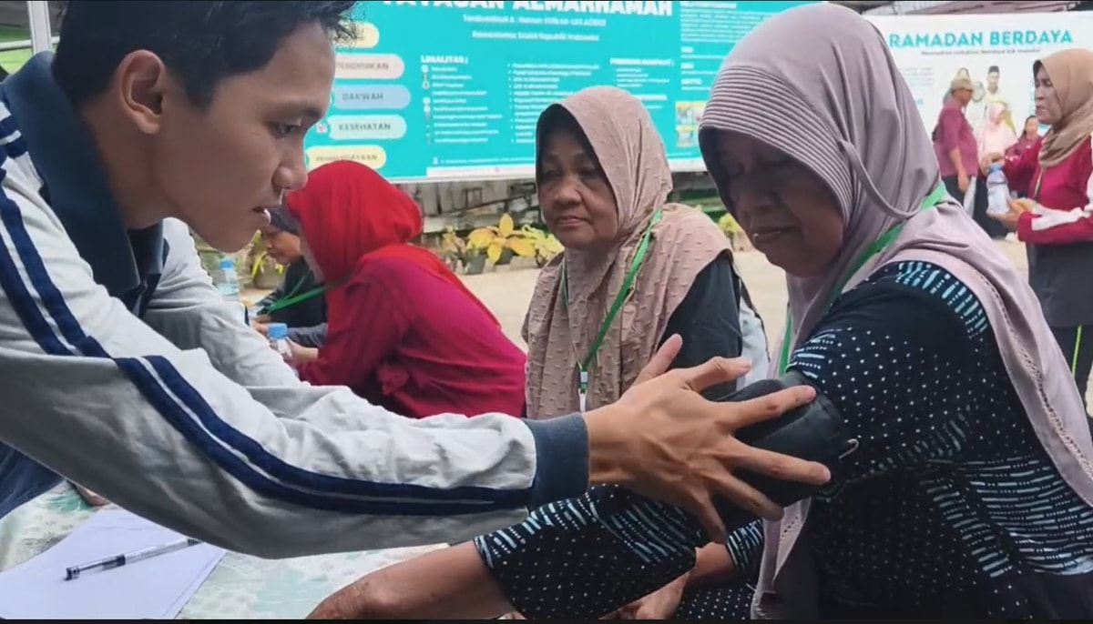 Mahasiswa BEM FIKES UBT memasangkan alat pemeriksa tekanan darah pada lansia almarhamah