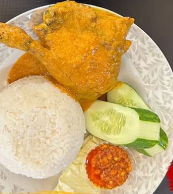 Bebek panggang rempah berwarna kuning keemasan dengan nasi dan timun