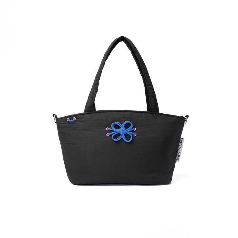 Blume Tote Bag hitam dari Into The Lume dengan hiasan tali biru berbentuk bunga, totebag stylish dan fungsional untuk daily use.